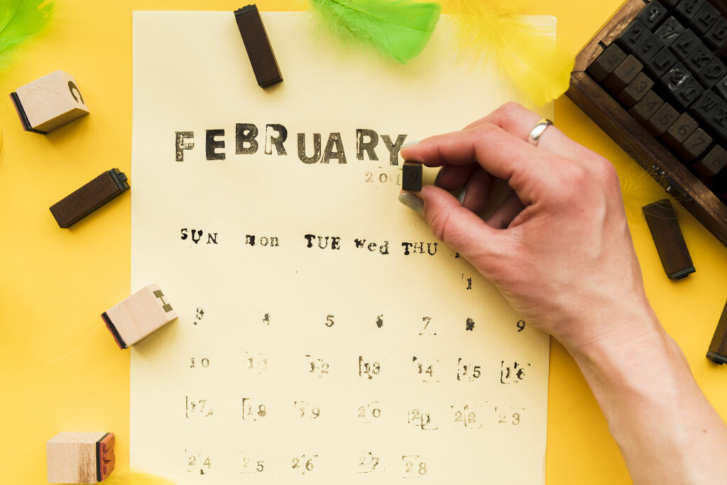 person-making-february-calendar-with-typographic-blocks-yellow-background-1024x683.jpg